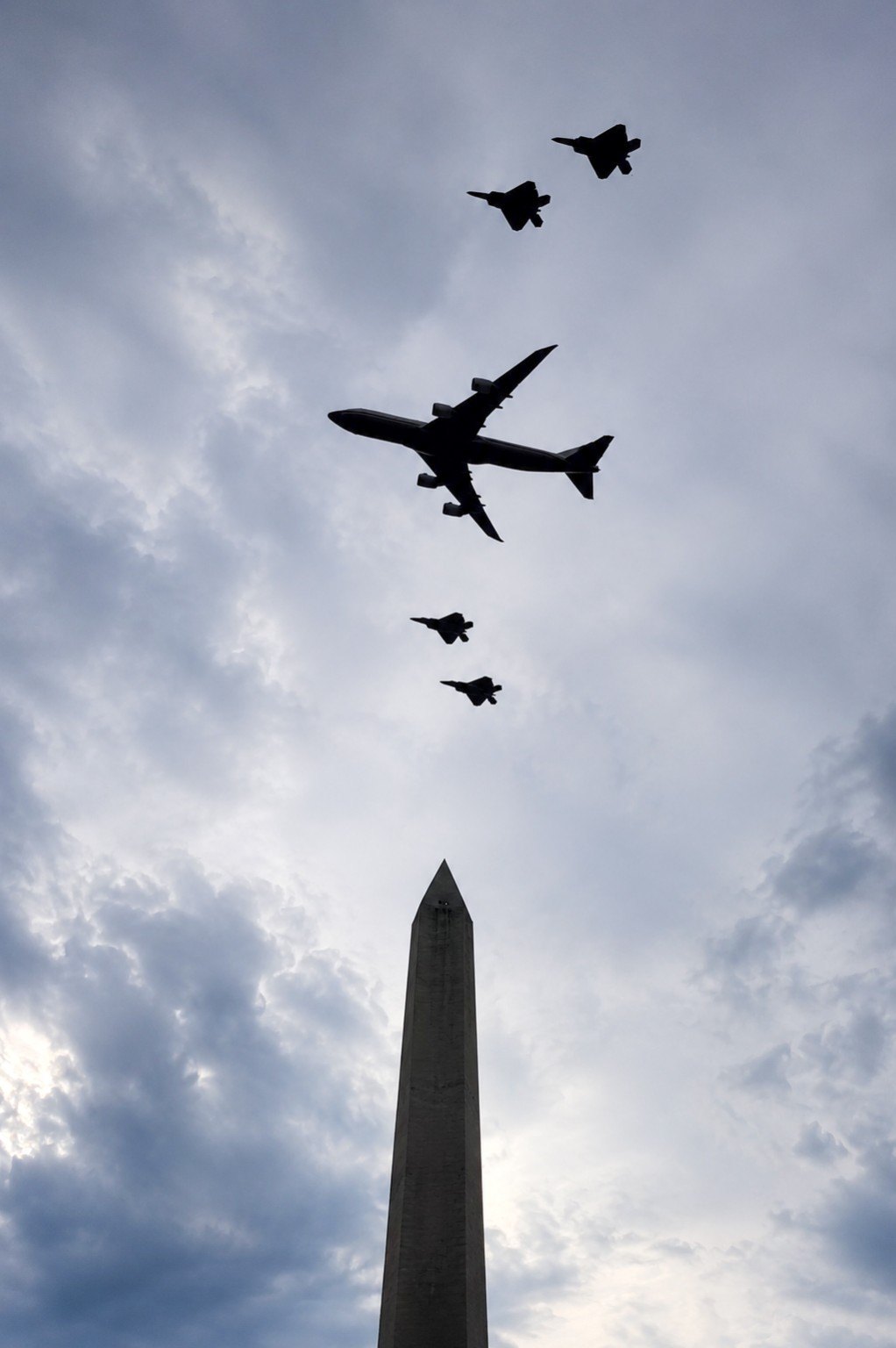 Air Force One and four fighter escorts flying above the Washington Monument.